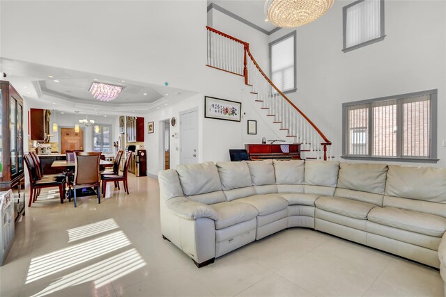 living room with stairs, ornamental molding, recessed lighting, a raised ceiling, and a notable chandelier