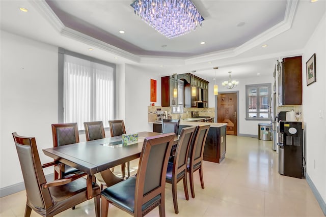 dining space featuring baseboards, ornamental molding, recessed lighting, a tray ceiling, and an inviting chandelier
