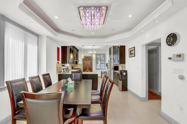 dining space featuring baseboards, a tray ceiling, a notable chandelier, and ornamental molding