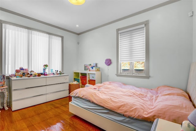 bedroom with wood finished floors and ornamental molding