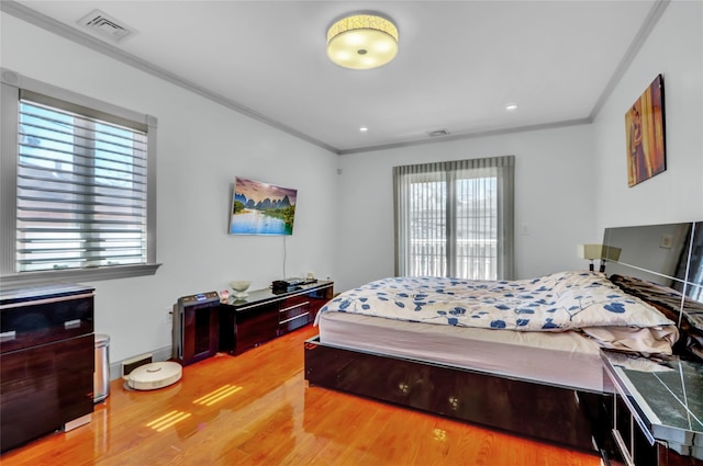 bedroom with baseboards, visible vents, wood finished floors, and ornamental molding