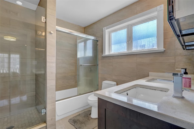 bathroom featuring tile walls, double vanity, toilet, tile patterned floors, and a sink
