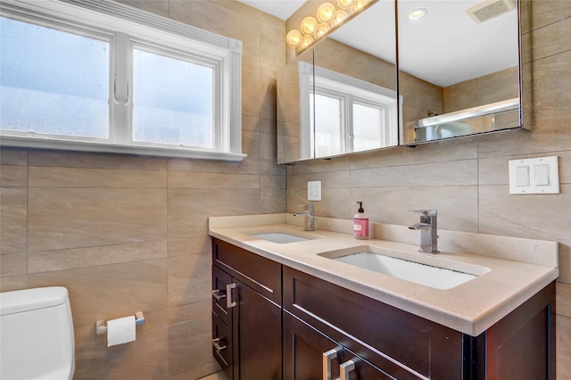 full bath featuring tile walls, visible vents, toilet, and a sink
