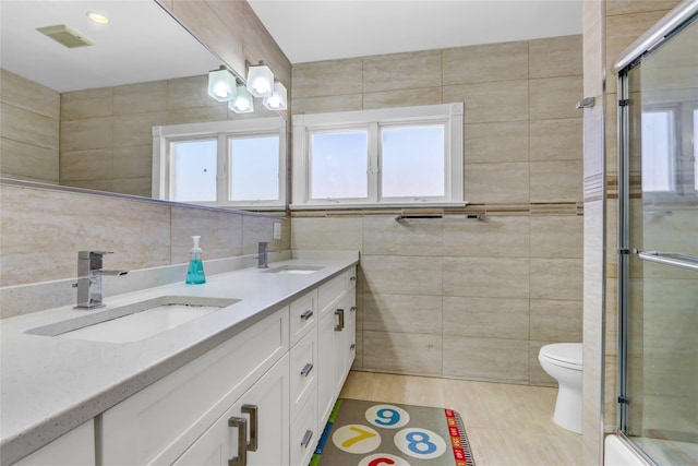 full bathroom featuring a sink, an enclosed shower, and tile walls