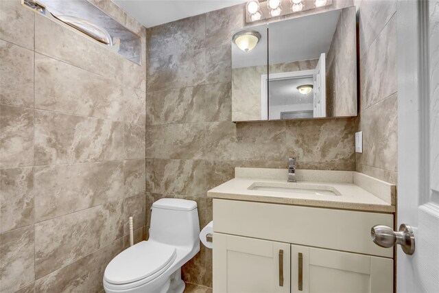 half bathroom with tile walls, toilet, and vanity