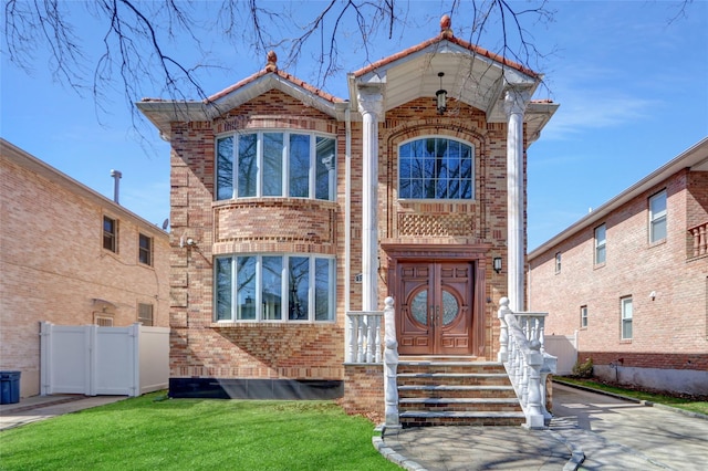 view of front facade featuring a front yard, fence, and brick siding
