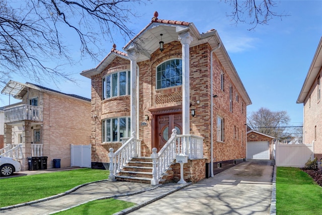 view of front of property with brick siding, a garage, an outdoor structure, and fence