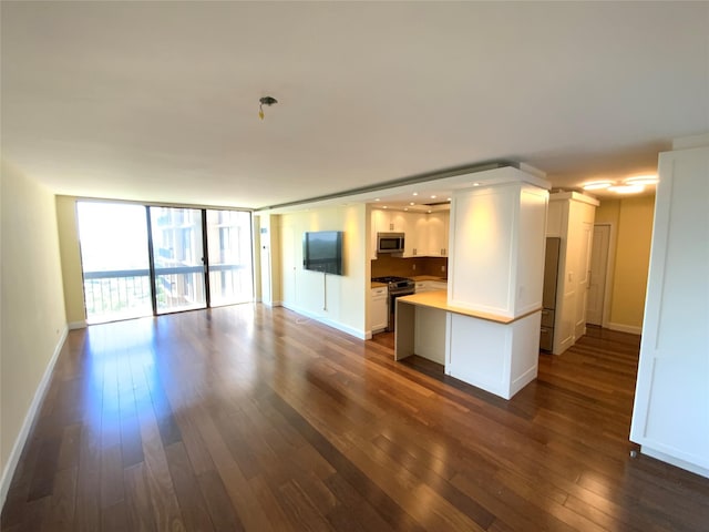 unfurnished living room featuring dark wood-style flooring, baseboards, and recessed lighting
