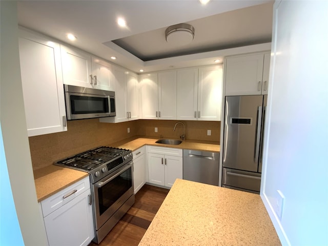 kitchen featuring stainless steel appliances, a sink, white cabinets, recessed lighting, and decorative backsplash