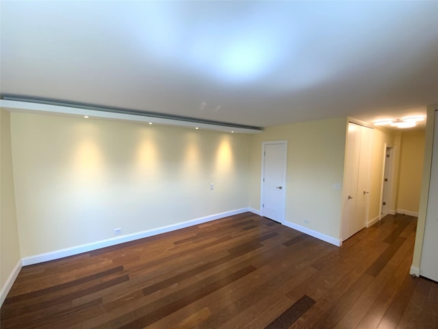 empty room featuring dark wood-type flooring and baseboards