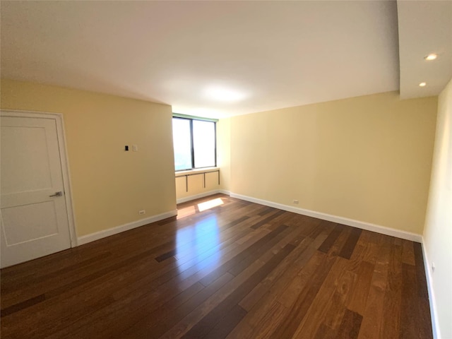 spare room with dark wood-style floors, baseboards, and recessed lighting