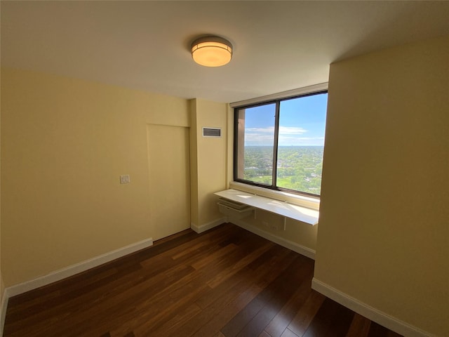 unfurnished room featuring dark wood-type flooring and baseboards
