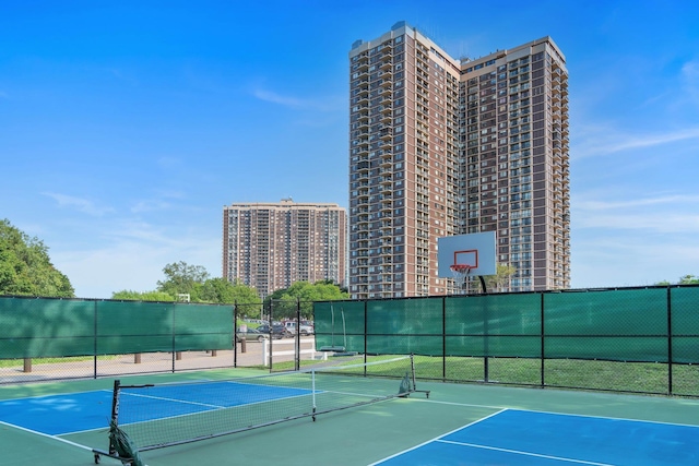 view of sport court with fence, a tennis court, and a city view