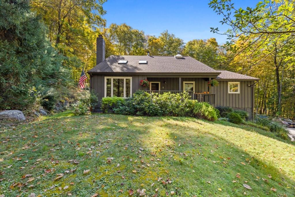 9 Equestrian Acres, Brewster, NY 10509 - rear view of house featuring board and batten siding, a chimney, and a lawn