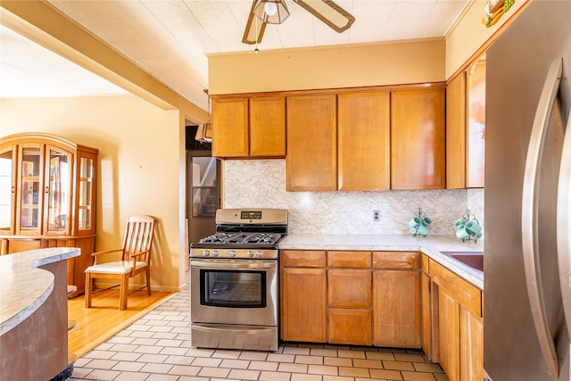 675 N Oakwood Rd, Laurel, NY 11948 - kitchen featuring brown cabinets, ceiling fan, light countertops, backsplash, and appliances with stainless steel finishes