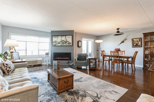 living area with plenty of natural light, a glass covered fireplace, and wood finished floors