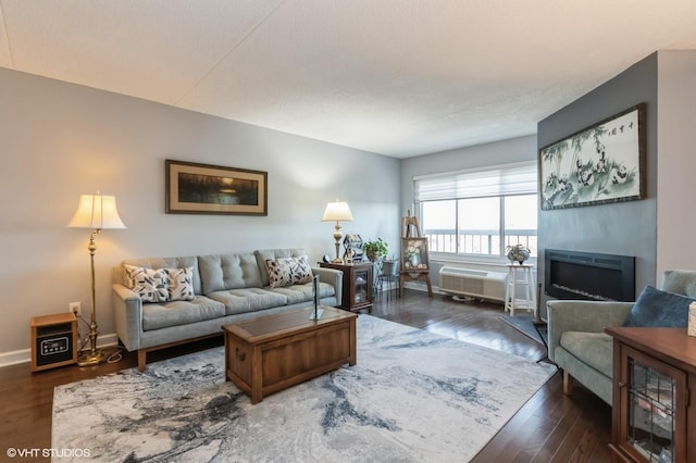 living area featuring a fireplace, dark wood-style flooring, and baseboards