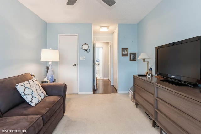 living room featuring light colored carpet, baseboards, and ceiling fan