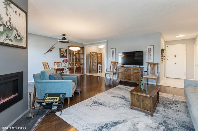 living area with a fireplace, baseboards, and wood finished floors