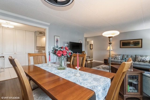 dining room featuring visible vents, a textured ceiling, ornamental molding, and wood finished floors