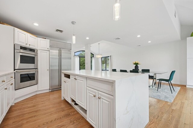 45 Nichols Rd, Huntington Station, NY 11746 - kitchen featuring a kitchen island, stainless steel appliances, visible vents, white cabinets, and light wood-style floors