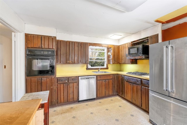 65 Hickory Ln, Bedford, NY 10506 - kitchen featuring a sink, brown cabinets, black appliances, and light countertops