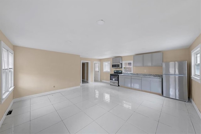 unfurnished living room featuring light tile patterned floors, baseboards, and a healthy amount of sunlight