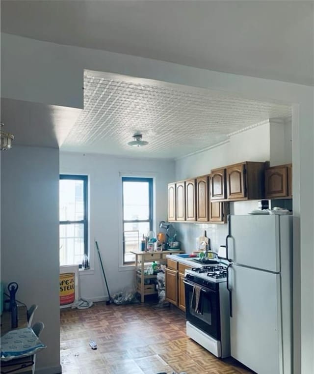 kitchen with light countertops, gas stove, and freestanding refrigerator
