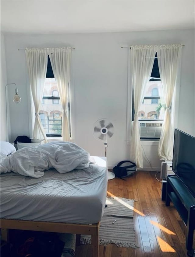 bedroom featuring multiple windows, cooling unit, and wood-type flooring