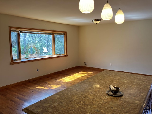 empty room with baseboards, visible vents, and wood finished floors