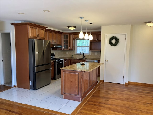 kitchen featuring a sink, freestanding refrigerator, gas range, light wood-style floors, and decorative backsplash