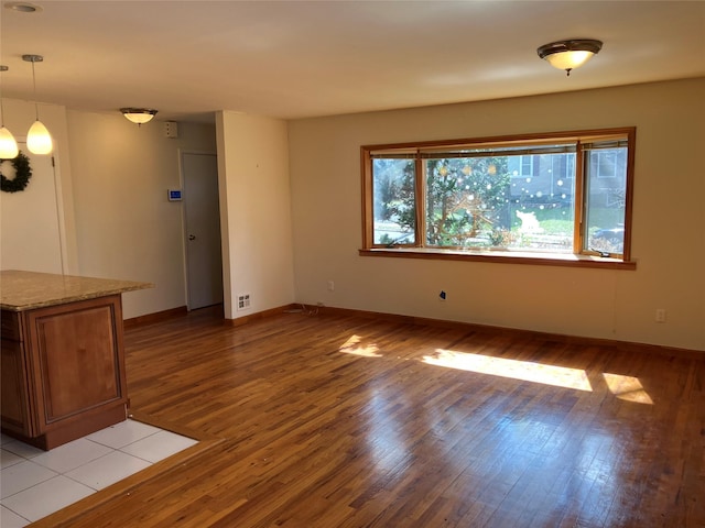 unfurnished living room with baseboards, visible vents, and light wood-type flooring