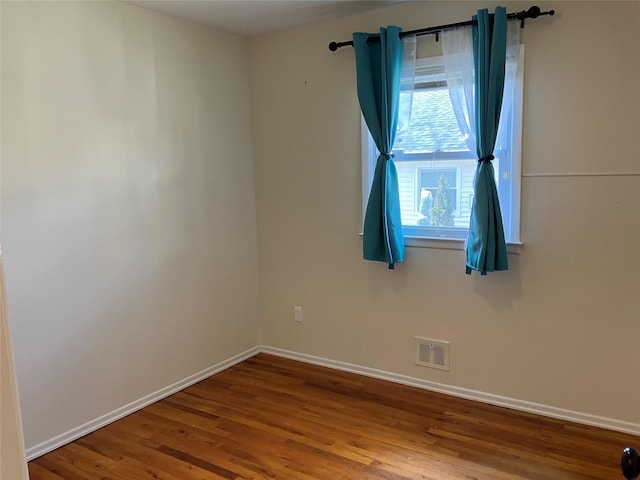 spare room featuring wood finished floors, baseboards, and visible vents
