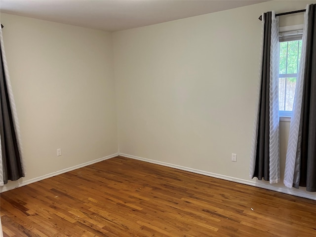 spare room featuring baseboards and wood finished floors