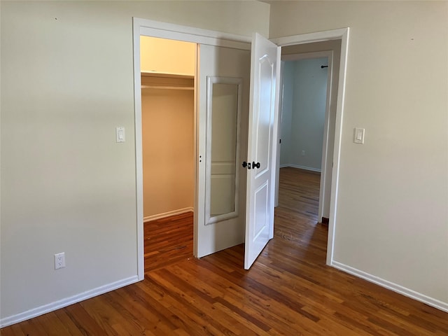 unfurnished bedroom featuring baseboards, a closet, and wood finished floors