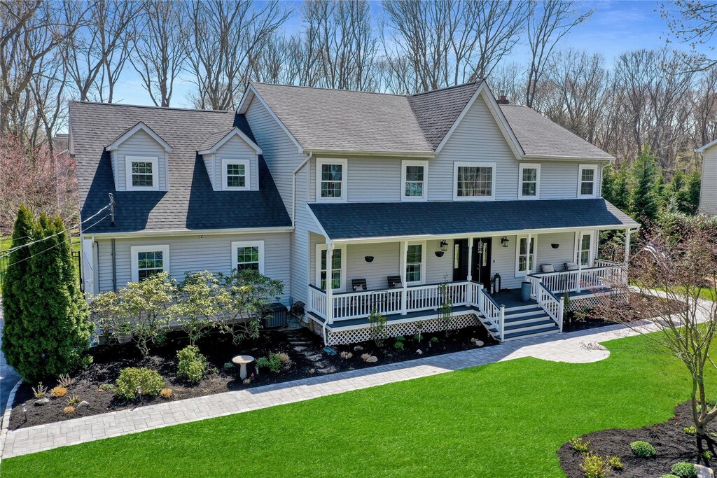 view of front of property featuring a shingled roof, covered porch, and a front yard