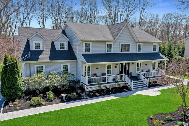 view of front of property featuring a shingled roof, covered porch, and a front yard