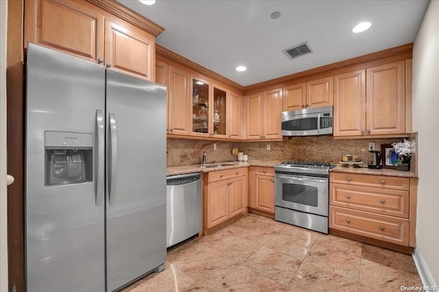 kitchen with backsplash, a sink, light stone counters, visible vents, and appliances with stainless steel finishes