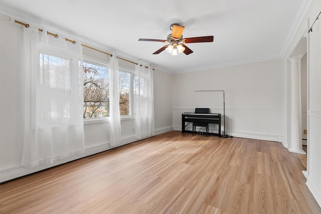 unfurnished room featuring decorative columns, ornamental molding, a ceiling fan, and light wood-type flooring