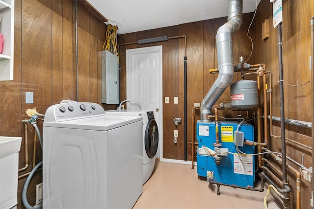washroom featuring wood walls, a heating unit, washing machine and dryer, laundry area, and electric panel