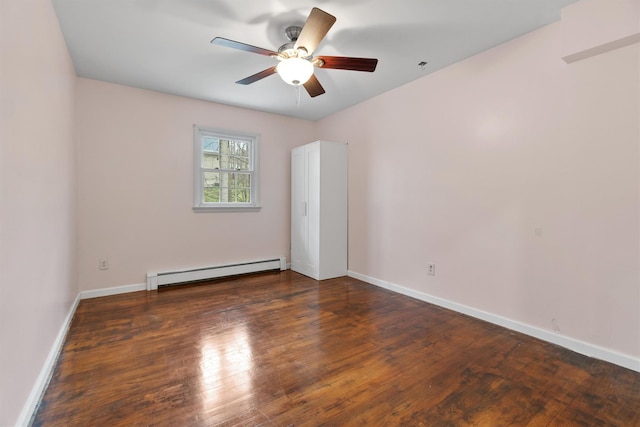 empty room featuring baseboards, baseboard heating, wood finished floors, and a ceiling fan