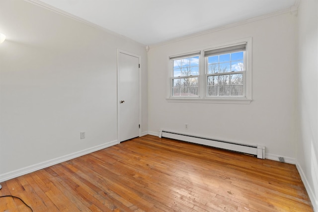spare room featuring baseboards, baseboard heating, light wood-style flooring, and ornamental molding