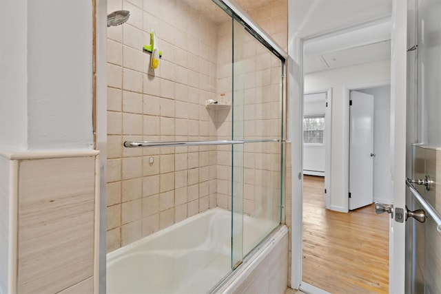 bathroom featuring wood finished floors, tiled shower / bath, and a baseboard radiator