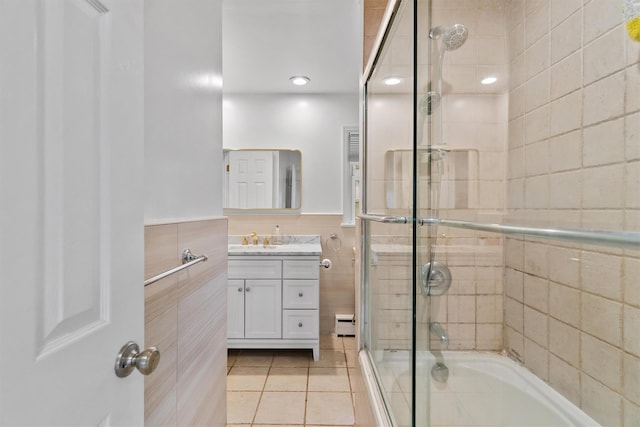 bathroom with tile patterned flooring, vanity, tile walls, a baseboard radiator, and combined bath / shower with glass door