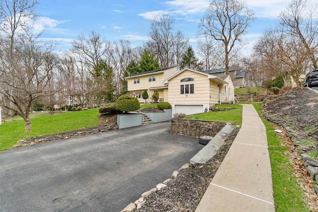 view of side of property featuring aphalt driveway, a yard, and an attached garage