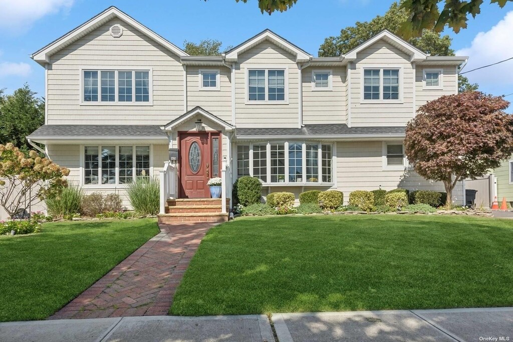view of front of house featuring a front lawn and roof with shingles