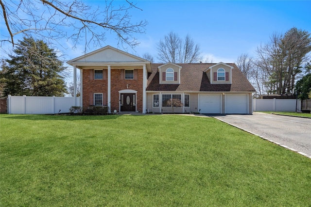 greek revival inspired property featuring a front lawn, fence, brick siding, and concrete driveway