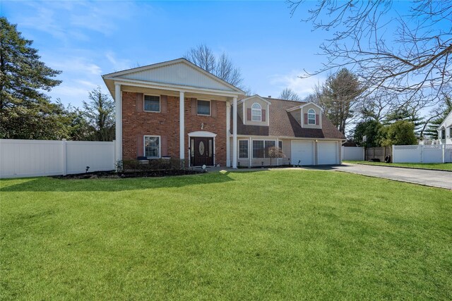 neoclassical / greek revival house with a front yard, fence, brick siding, and concrete driveway