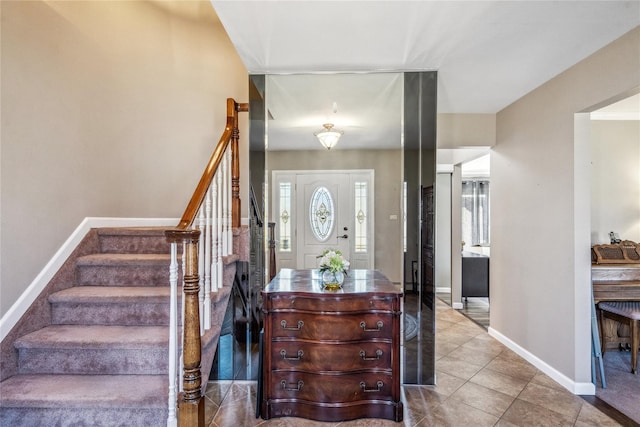 tiled foyer featuring baseboards and stairs