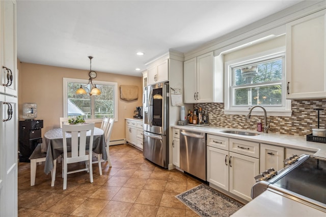 kitchen featuring light countertops, backsplash, a sink, a baseboard radiator, and appliances with stainless steel finishes